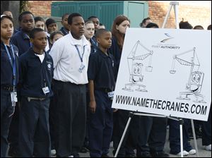 Fifth graders from the Maritime Academy downtown listen as representatives of the Toledo-Lucas County Port Authority announce a contest, open to area youth, to name two new cranes that will be arriving in May for use at the Port of Toledo. From left in front are Myah Stewart, Lance Chaney, David Smith, and Anthony Reese, standing next to a poster done by The Blade's editorial cartoonist, Kirk Walters. The Name the Cranes contest begins today and continues through April 30. Area students can submit their suggestions to the Web site namethecranes.com.