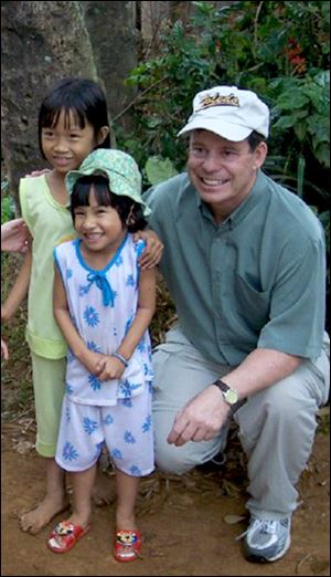 Veteran Fred Grimm poses for a picture with children of the Song Ve Valley, where he plans on building a school.