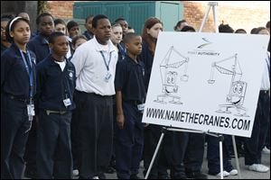 Fifth graders from the Maritime Academy downtown listen as representatives of the Toledo-Lucas County Port Authority announce a contest, open to area youth, to name two new cranes that will be arriving in May for use at the Port of Toledo. From left in front are Myah Stewart, Lance Chaney, David Smith, and Anthony Reese, standing next to a poster done by The Blade's editorial cartoonist, Kirk Walters. The Name the Cranes contest begins today and continues through April 30. Area students can submit their suggestions to the Web site namethecranes.com.
