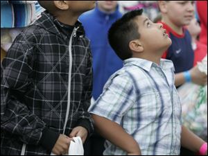 Julian Hill, 9, at left, keeps his eyes on the sky on a blustery day outside the Church on Strayer in Monclova Township.