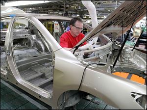 A component goes into a Camry at Toyota's factory in Georgetown, Ky. Camry models are included in the incentive programs.