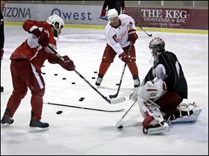Detroit's Darren Helm, left, and Kirk Maltby take shots on goalie Jimmy Howard during practice.
