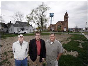 Tom Ehmke, head of Habitat for Humanity in Wood County, left, and Habitat board President Staten Middleton, center, received a deed for this vacant property from Dan Van Vorhis, right. 