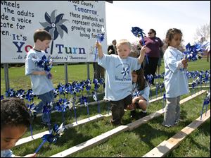 Among those who helped set up pinwheels representing reports of child abuse or neglect are, from left, Thomas Buckman, Tyler Amos, Patrick Contreras holding pinwheels aloft, and Raghad Alahdal.