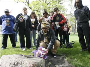 Wendy Robinson, whose son, Donnie, was murdered, lays flowers on a memorial as other family members of murder victims watch on the Lucas County Courthouse lawn. The Parents of Murdered Children and the county prosecutor's office organized the vigil last evening in observance of Victims' Rights Week.