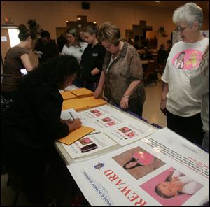 CTY nevaeh 26p   04/026/2010       The Blade/Lori King  Risa Thompson, left, signs out posters during the Nevaeh Buchanan Reward Poster Campaign at the Moose Lodge in Monroe, Mich. Watching at right is Nevaeh's great aunt, Diana Lawson.
