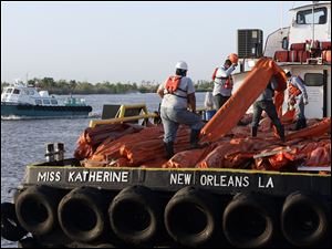 Workers load a vessel to help contain oil leaking from last week's oil rig explosion in the Gulf of Mexico. Officials raised leak estimates to 5,000 barrels, or 200,000 gallons, of oil a day.