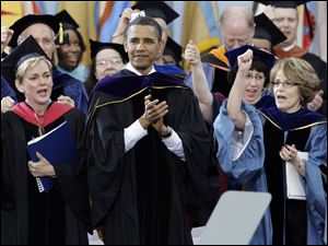 President Barack Obama applaudes as Michigan Gov. Jennifer Granholm, left, and UM President Mary Sue Coleman, right, sing "The Victors" during the commencement ceremony.