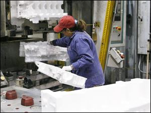 Defiance employee Pearl Reyna inserts halves of foam engine-casting forms into a machine that glues them together. 
