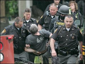 Sheriff Mark Wasylyshyn, lower right, leads the Wood County Sheriff's Department as they remove Keith Sadler from his home Friday morning in Stony Ridge.