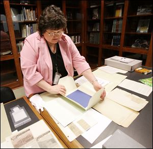 Irene Martin examines some of the documents for which she is responsible at the main library of the Toledo-Lucas County system. She is to present a preservation how-to program Saturday.