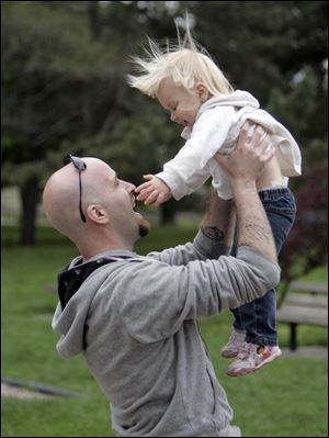 Former Marine Eric Bartkowiak of Toledo, playing with his daughter Lillie, 2, is among the veterans who have been assisted by Arms Forces. 