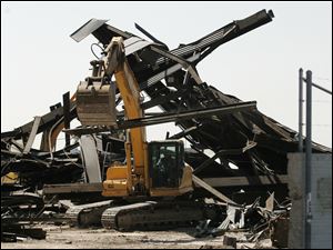 Employees of Burge Wrecking LLC move some of the debris that will be cut up and recycled from the 90-foot-high structure they razed Monday afternoon.