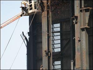 Randy Thatcher uses a cutting torch to deepen a notch in a beam on a structure to be razed at the old Acme coal-fired power plant on Front Street in East Toledo.