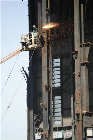 Randy Thatcher uses a cutting torch to deepen a notch in a beam on a structure to be razed at the old Acme coal-fired power plant on Front Street in East Toledo.