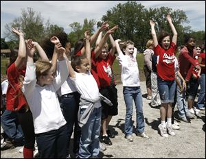 Vera Okonski, left, and Jalycia Price do the wave with their Elmhurst Elementary schoolmates as they wait for the festivities to begin. Parents, staff, and neighbors raised funds for the new field.