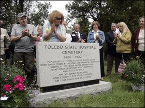 Jane Weber, a member of the Toledo State Hospital Cemetery Reclamation Project, looks at the monument at the dedication. More than 140 people attended.