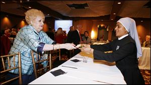 Rose Marie Strayer, a resident at Little Sisters of the Poor in Oregon, is served by Sister Florian D'Souza at the home's fund-raiser at the Pinnacle in Maumee.
