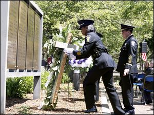 Officer Katrina Welch-Bills of the Toledo Police Department's honor guard places a wreath at the Toledo Police Memorial Garden to honor colleagues who have died in the line of duty. Behind her is Chief Mike Navarre. 