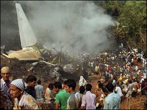 Civilians look on as Indian firefighters and rescue personnel gather around the site of an Air India plane that crashed in Mangalore, in the southern Indian state of Karnataka, Saturday, May 22, 2010. The Air India Express plane trying to land in the rain at a tricky hilltop airport in southern India overshot the runway, crashed and burst into flames at dawn Saturday, killing nearly 160 people, officials said. At least eight survived.