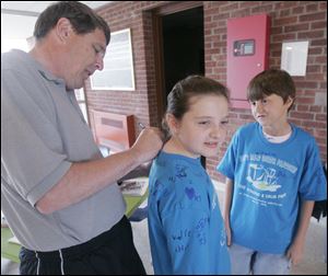 St. Joseph School physical education teacher Cary Weaver signs third grader Belle Bruno's T-shirt while her classmate, Mason Orians, looks on before the start of a race as part Positive Addiction Week.