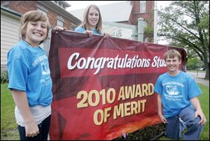 With St. Joseph school's sign noting its designation by the Red Robin Foundation are students, from left, Juliane Gillen, Catherine Coulter, and Tyler Perino.