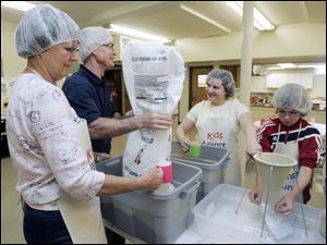 From left, Joy Hodak, Rick Ellis, Theresa Buehler, and Derek Huddleston pack meals in assembly-line fashion at St. Paul Lutheran Church in Maumee as part of the Kids Against Hunger project. The members' goal was to assemble 30,000 food packages to be shipped to Haiti.