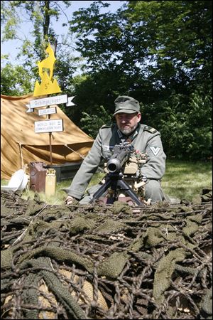 Toledoan Mark Pacholski, portraying a member of the German Gebirgsjager, or mountain infantry, watches the enemy from behind barbed wire and sandbags.