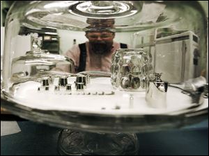 Dan Newcombe, whose job is to make sure the weights and measures in Maine are true, looks into a glass enclosure in a lab containing precision weights that are used to calibrate other weights.