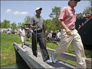 Tiger Woods, following Steve Stricker across a bridge yesterday, says the neck injury that caused him to withdraw from his last tournament is getting better. The Memorial begins today.