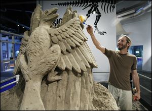 Carl Jara works on an archaeopteryx — a Jurassic Period reptilian bird — as part of a 25-ton sand sculpture at the Imagination Station. The reigning world-champion sand sculptor is to finish the piece for Thursday night's Members Event at the science center.