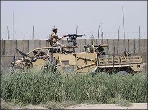 NATO soldiers secure an area after suicide attackers attacked a police training center in Kandahar. The attack yesterday killed an American police trainer and a Nepalese security guard.