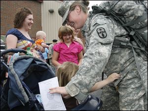 Spc. Amanda English of Perrysburg gets a hug from Alexis Gallagher, 4, of Millbury. Behind them are, from left, Alexis' mother, Theresa Emerick, holding 7-month-old Steven Fowler, and Shelbylee Hoff, 8, of Moline.