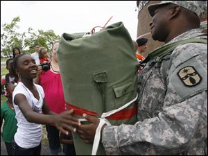 Spc. Lorenzo Oliver of the Ohio National Guard's 1483rd Transportation Company is welcomed home by family member Larshell Himon, 13, of Toledo. About 180 personnel from the company, which is based in Walbridge, were greeted by friends and relatives yesterday at Owens Community College after a one-year deployment to support Operation Iraqi Freedom efforts in the Middle East.