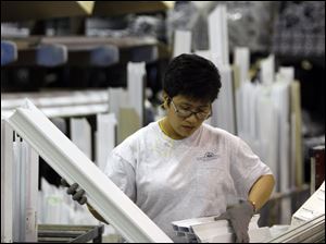 A worker manufactures windows at Northeast Building Products in Philadelphia. Fed chief Ben Bernanke told Congress yesterday the economy probably will plod ahead in the coming months.