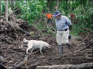 Carol Gilbert of Roanoke, Va., watches her dog Moki examine flood debris. Moki is trained to find remains.