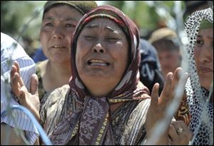 An Uzbek woman who says she fled from the southern Kyrgyz city of Osh after her family was killed weeps Monday as she stands in line in no-man's-land near the Uzbek village of Jalal-Kuduk waiting for permission to cross into Uzbekistan.