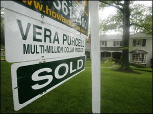 A 'sold' notice is added to a sign in Mt. Lebanon, Pa., but sales of previously occupied homes dipped in May.