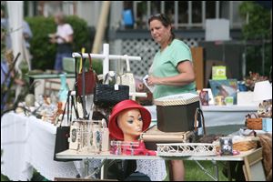 Katie Bedra of Oregon arranges her display of collectibles at the Maumee Valley Historical Society's annual lawn sale.