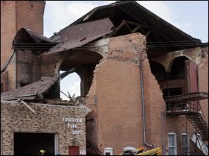 Firefighters clean up debris outside the Edgerton Village Hall. 