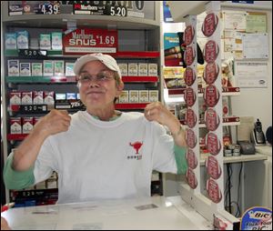 Shirley Loofborow shows off the shirt she received, along with a $48,500 check, because her Shirley's Carry Out sold a Powerball ticket that splits $97 million.