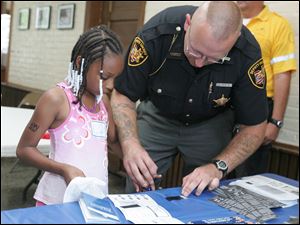 Lucas County Sheriff's Deputy Richard Veitch, Jr., fingerprints Quianna Ballard, 8.