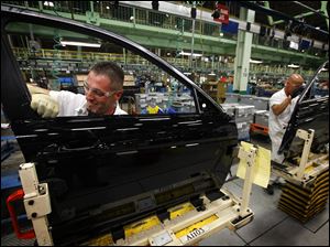 A worker installs fittings on doors at the Marysville, Ohio, factory, where too different models can be produced side by side on the same assembly line.