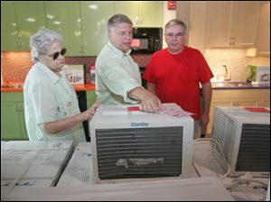 Chuck North, center, shows an air conditioner to Dolores Holdran and her son Jim Fry at the Appliance Center in Maumee, where demand for large window units has been strong.
