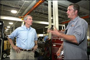 Rob Portman, left, speaks with Walter Sahloff, a shop foreman at Brennan Industrial Truck Co. in Holland. Mr. Portman toured the factory and spoke to workers there Wednesday.