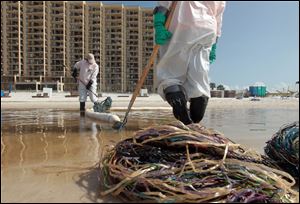 Workers use absorbent booms to collect oil and tar balls that have rolled in with the tide to land on Orange Beach, Ala. The BP spill is one of the worst environmental disasters in U.S. history.