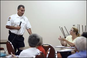 Capt. Rick Syroka listens to a question from Jenny Meyer of Toledo during a meeting downtown between Block Watch leaders and fire officials to talk about the city's arson epidemic.