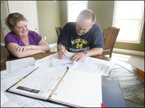 Beth and Scott Swartz go over plans for their new home in Millbury. A ranch house will take the place of their two-story home that was ripped away by a tornado on June 5.