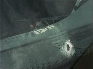 The windshield of Officer George Shaughnessy's police cruiser has a hole from one of several bullets fired at it in South Toledo.