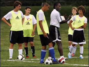Dennis Bailey, middle right, of the English Premier League gives instructions to local players at Pacesetter Park in Sylvania. 